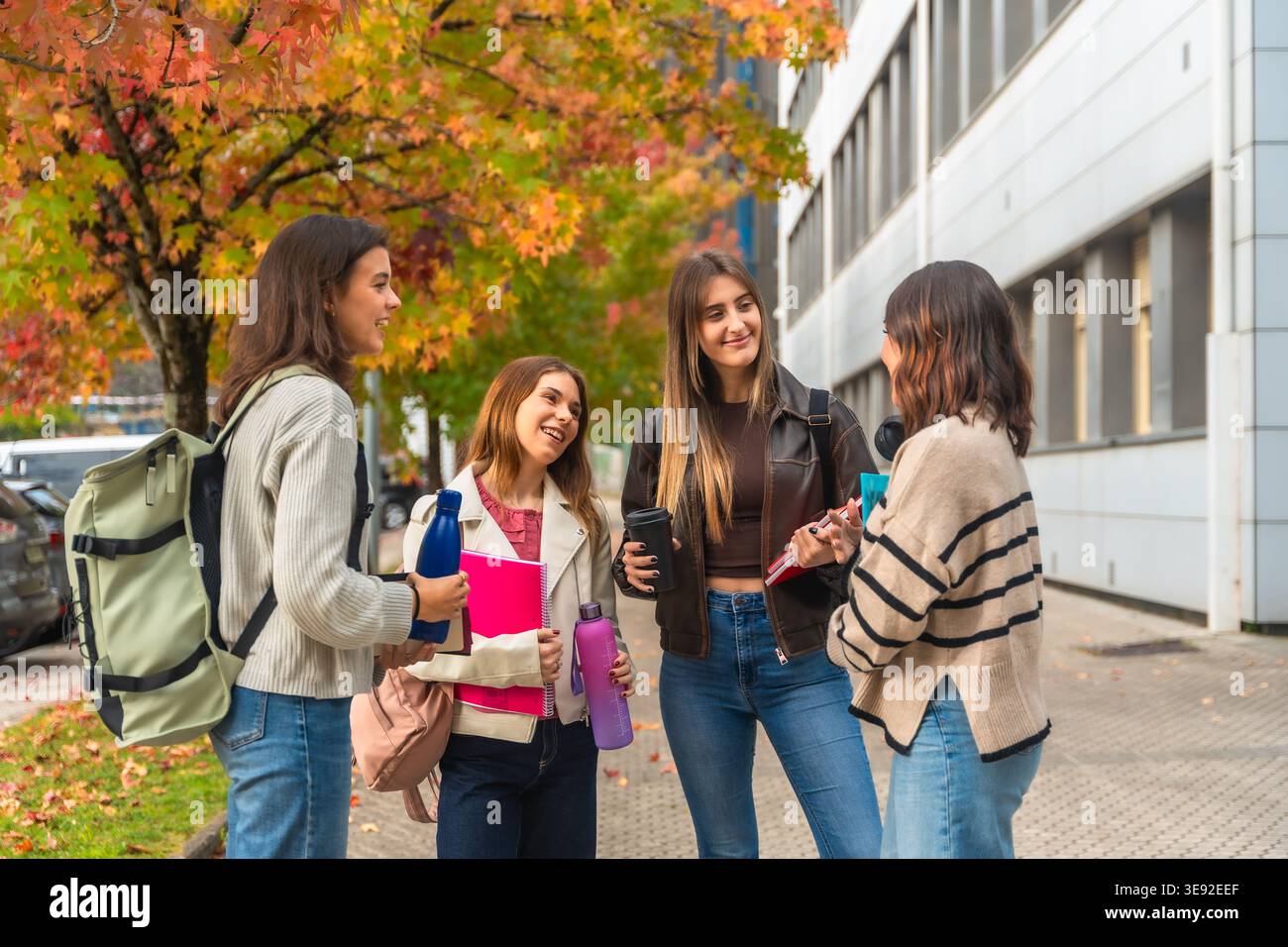 Studentesse che chiacchierano all'aperto nel campus universitario in autunno Foto Stock