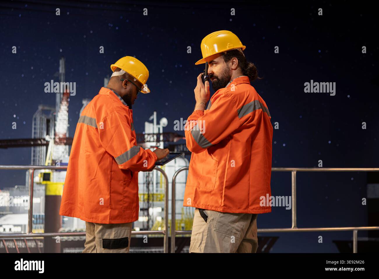 Perforazione di tecnici chiatte utilizzando una radio ricetrasmittente per coordinare le procedure di risposta alle emergenze. Operaio della piattaforma offshore che facilita la comunicazione rapida con il team tecnico durante le operazioni di turno tardivo Foto Stock