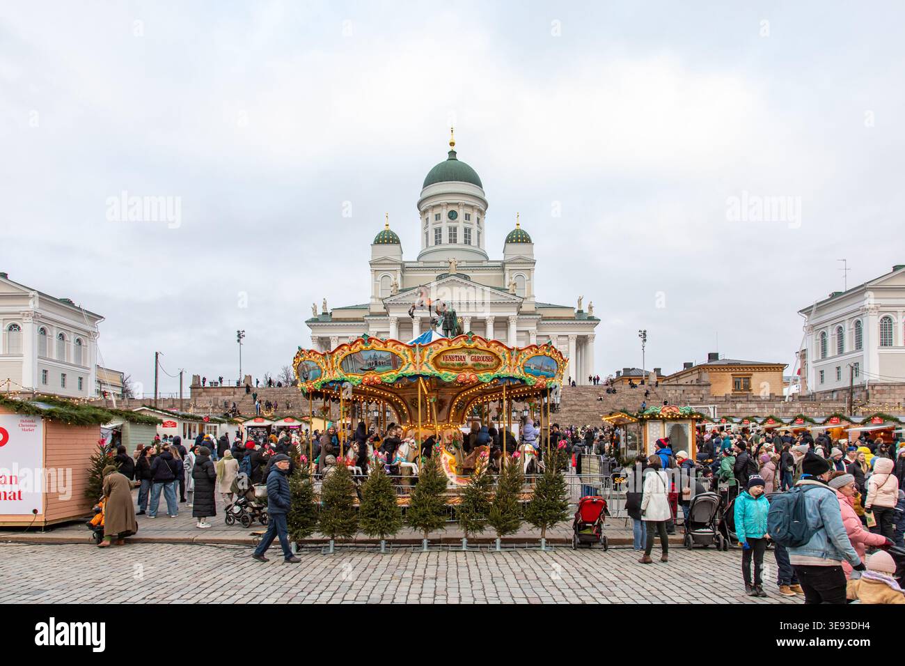Persone al Tuomaan Markkinat o al mercato di Natale di Helsinki in Piazza del Senato con la giostra veneziana di fronte e la cattedrale di Helsinki sullo sfondo Foto Stock