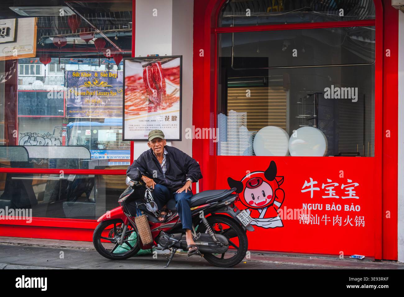 Uomo anziano seduto su una motocicletta di fronte alla facciata del Red Restaurant Foto Stock