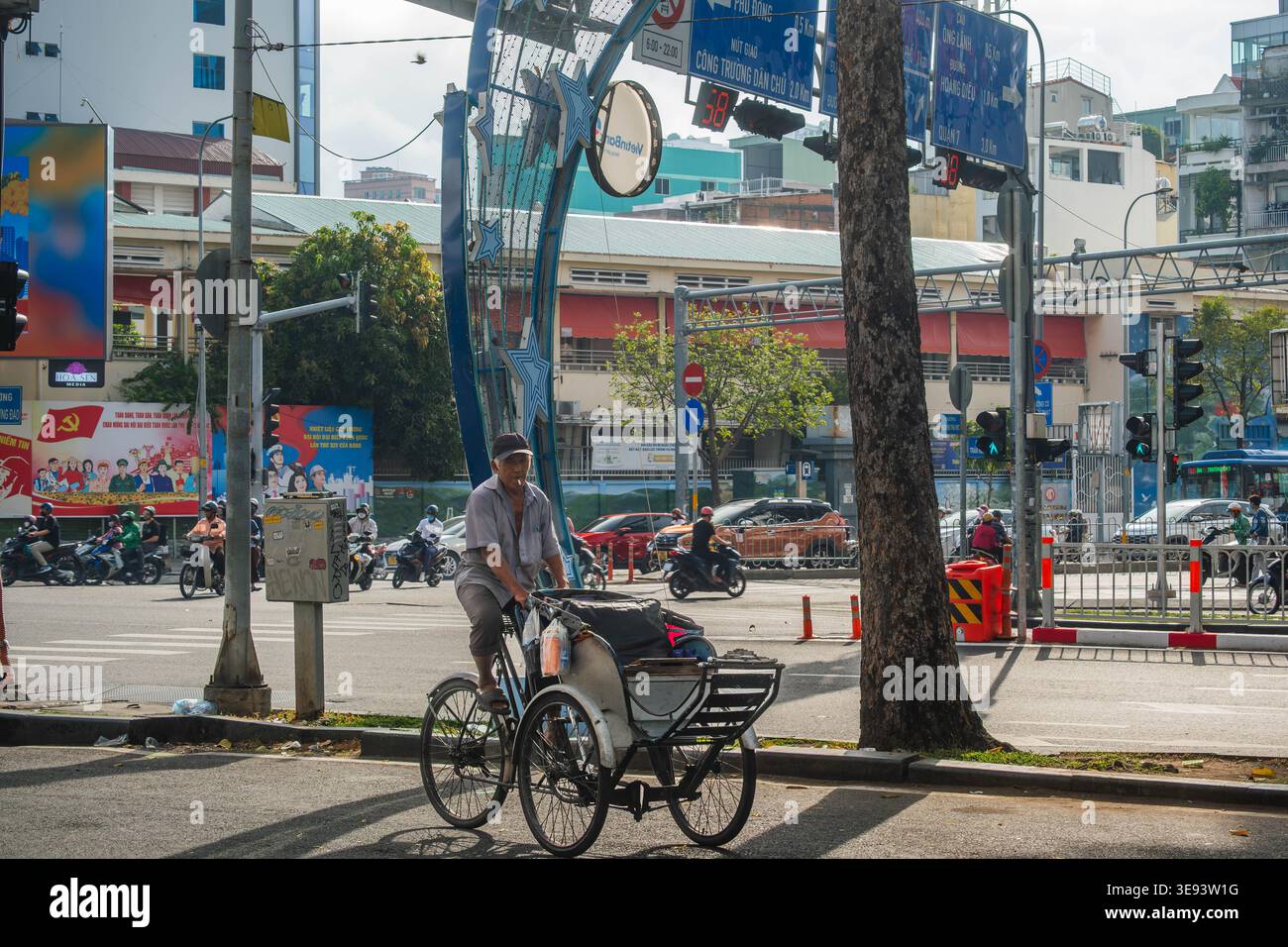 Cyclo driver che naviga in un incrocio occupato ad Hanoi Foto Stock