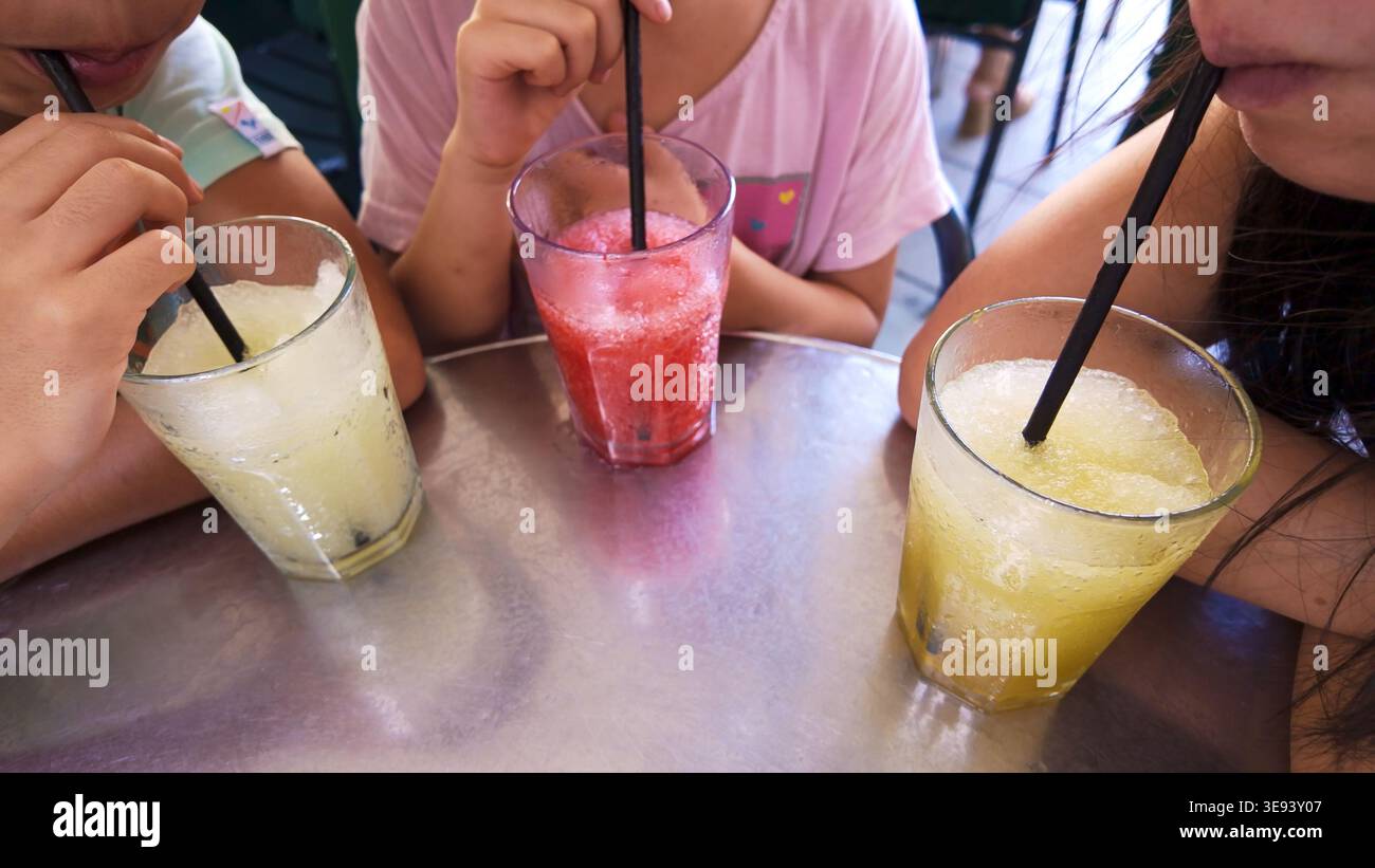I bambini si godono bevande fredde e rinfrescanti al bar all'aperto Foto Stock