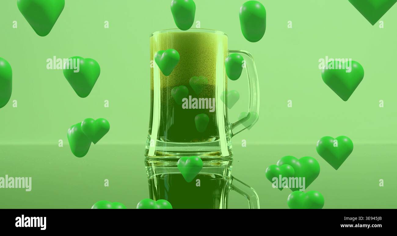 Mostra la tazza di birra in vetro con il manico che regge una bevanda verde spumeggiante su un piano lucido, gettando cuori verdi Foto Stock
