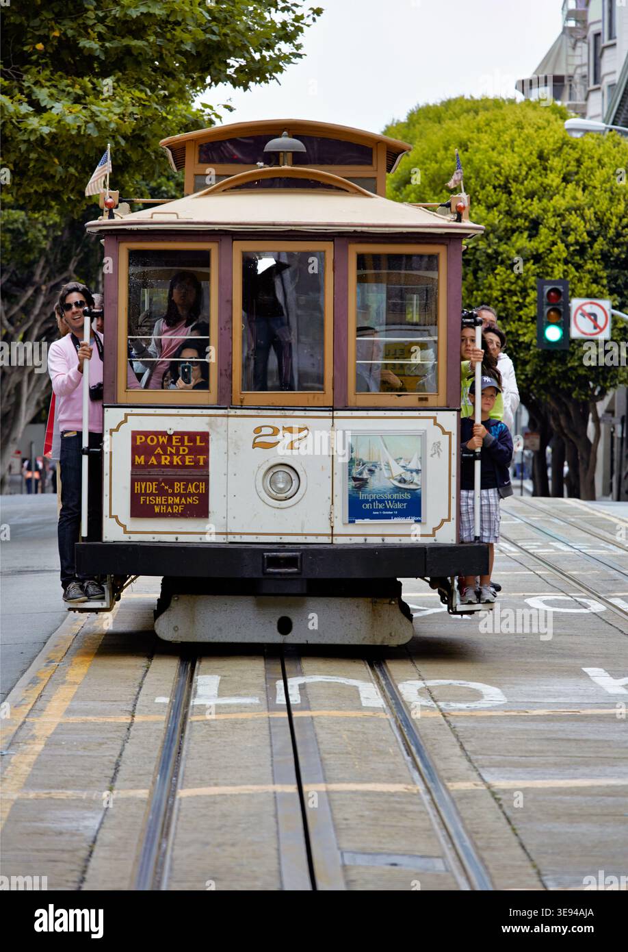 Una funivia si sposta lungo i binari di San Francisco. La gente si diverte mentre attraversa la città in una giornata di sole. Foto Stock