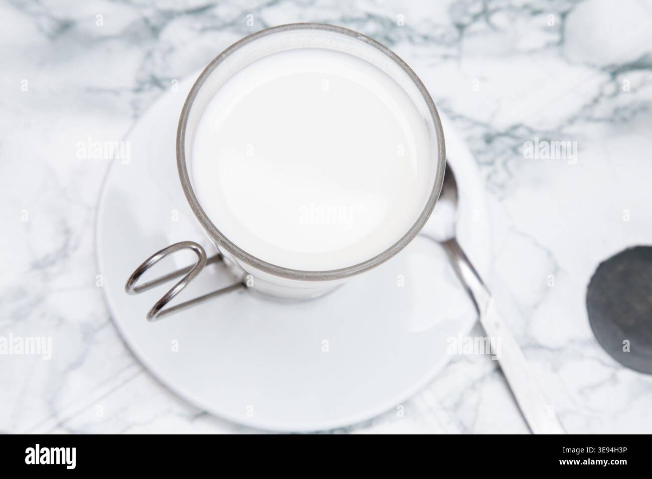 Elegante e moderno Cafe display con alto bicchiere di latte posizionato su piattino sullo sfondo in marmo Foto Stock