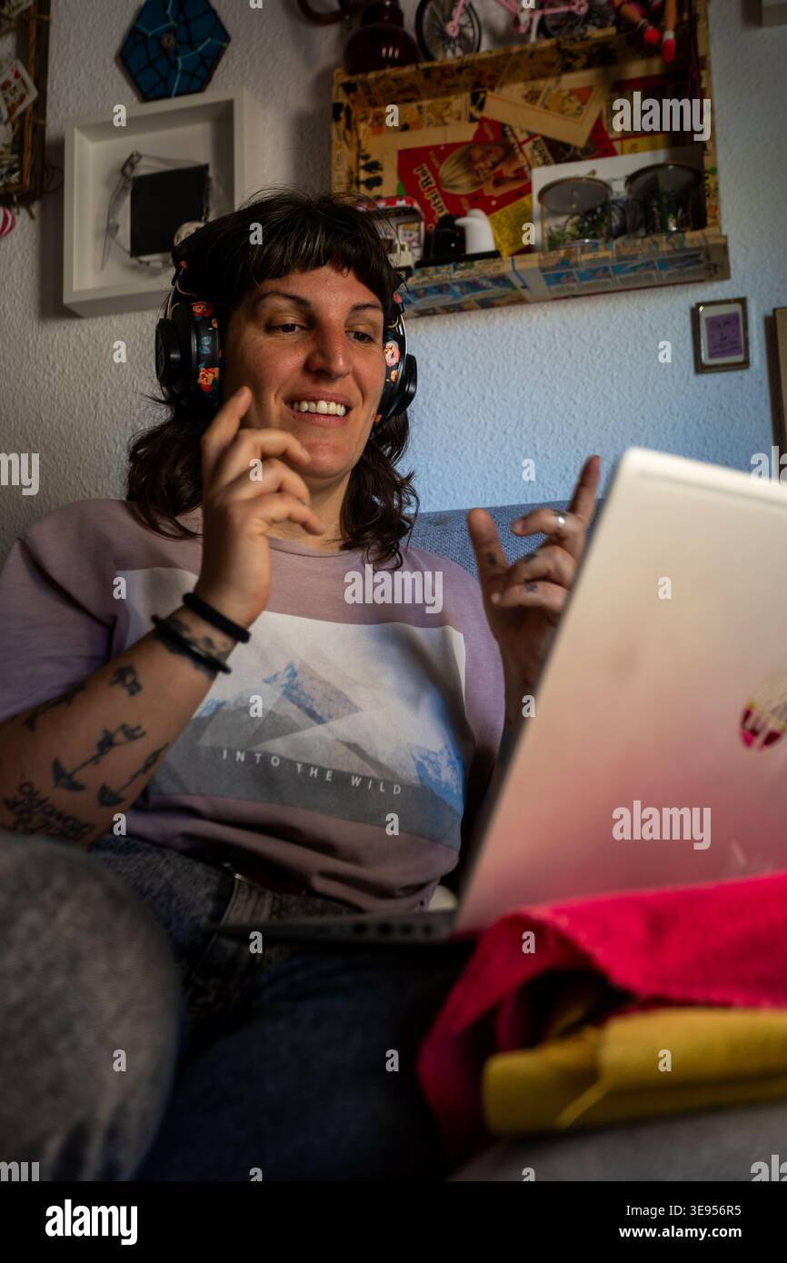 Giovane donna dallo stile indie alternativo che lavora con un notebook a casa per un autentico lavoro da remoto e uno stile di vita libero creativo con tatuaggi e pierci Foto Stock