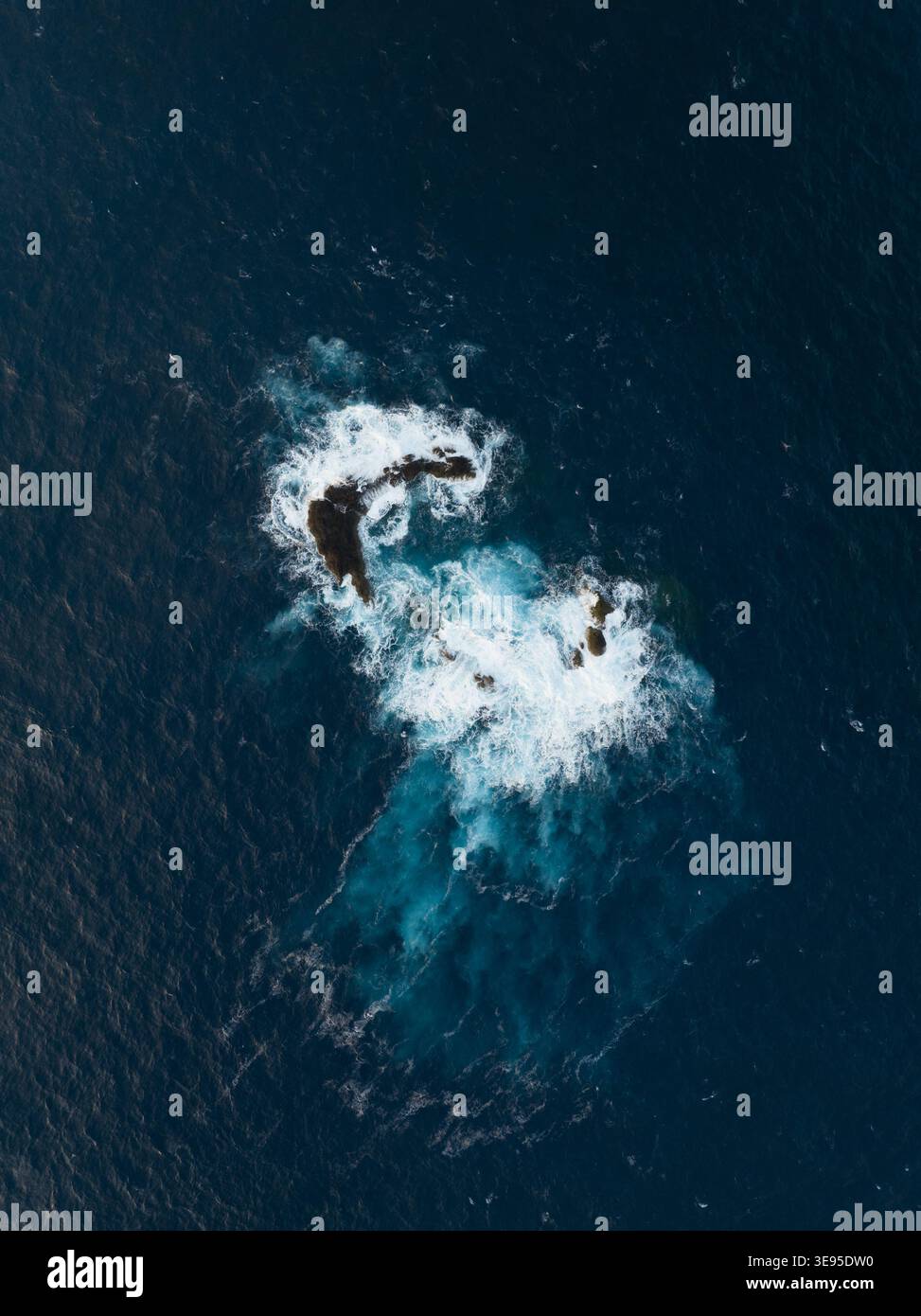 Vista aerea delle onde che si infrangono contro le formazioni rocciose vulcaniche nel blu profondo dell'Oceano Atlantico a Porto Moniz, Madeira, Portogallo. Foto Stock