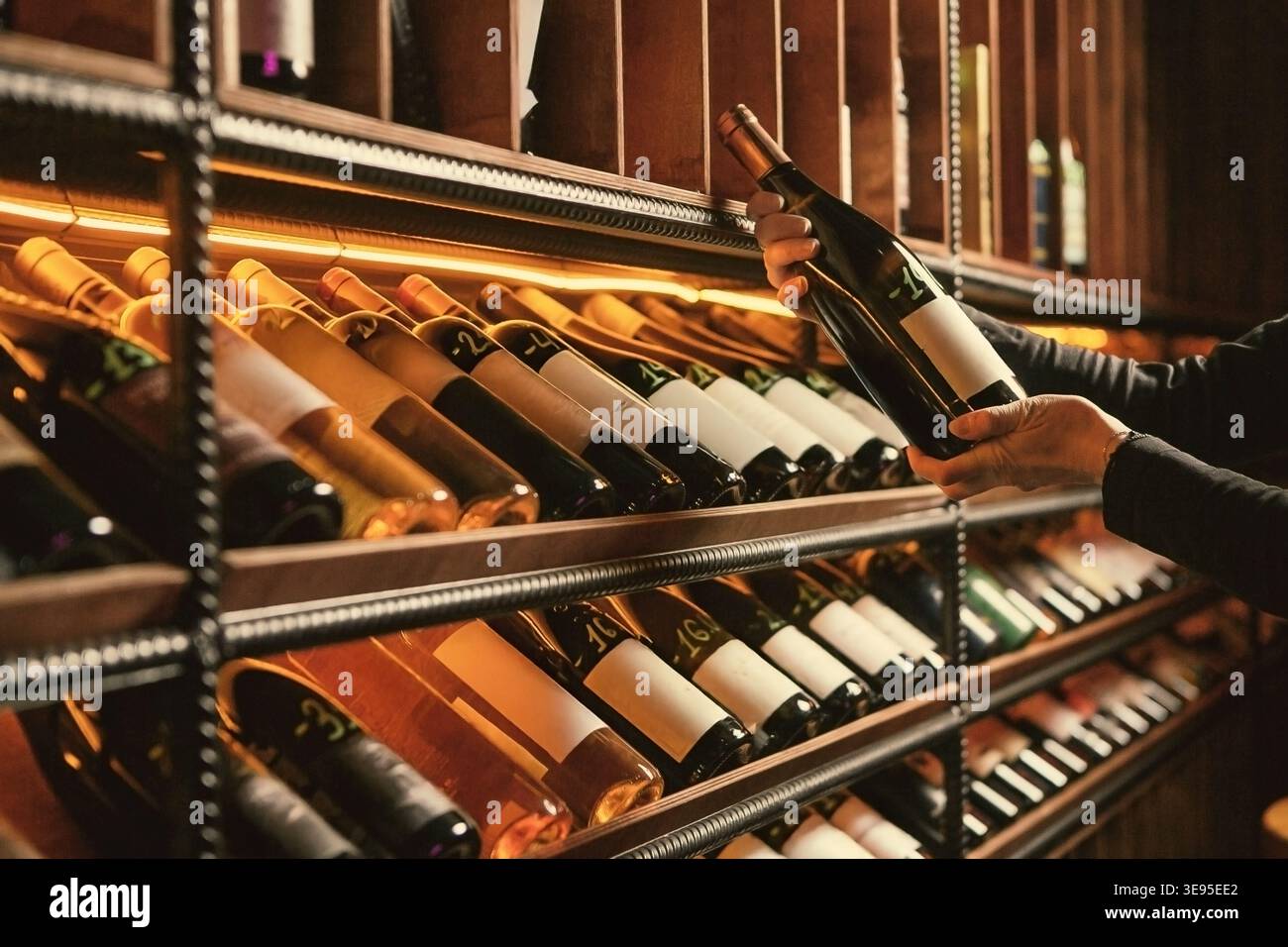 Estrazione della bottiglia di vino dal rack di legno Foto Stock