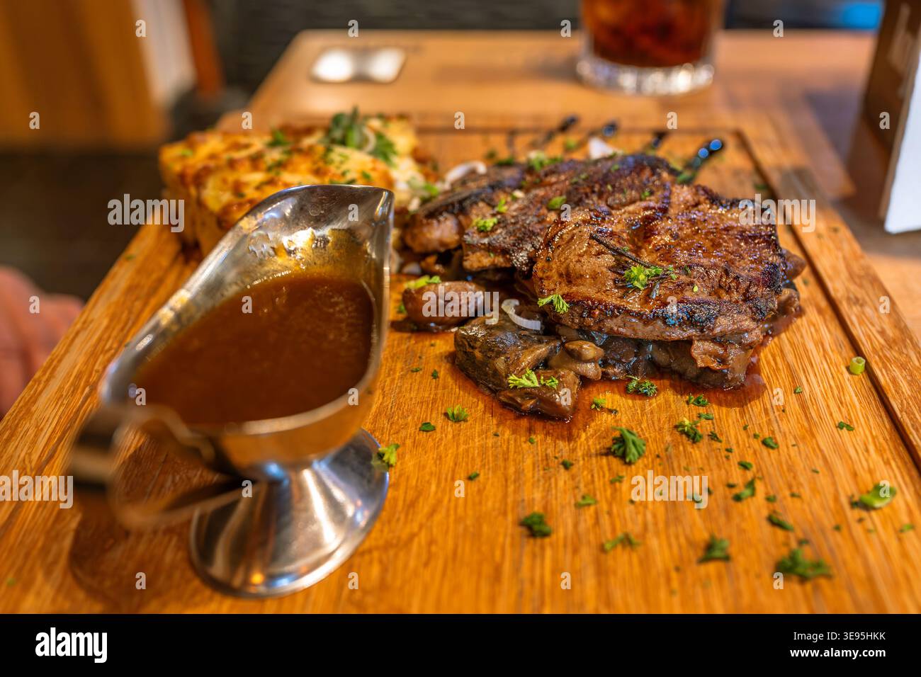 Carne di maiale grigliata, salsa piccante nella barca per salsa, ripieno pasquale su tavola di legno, cena sul tavolo del ristorante. Foto Stock