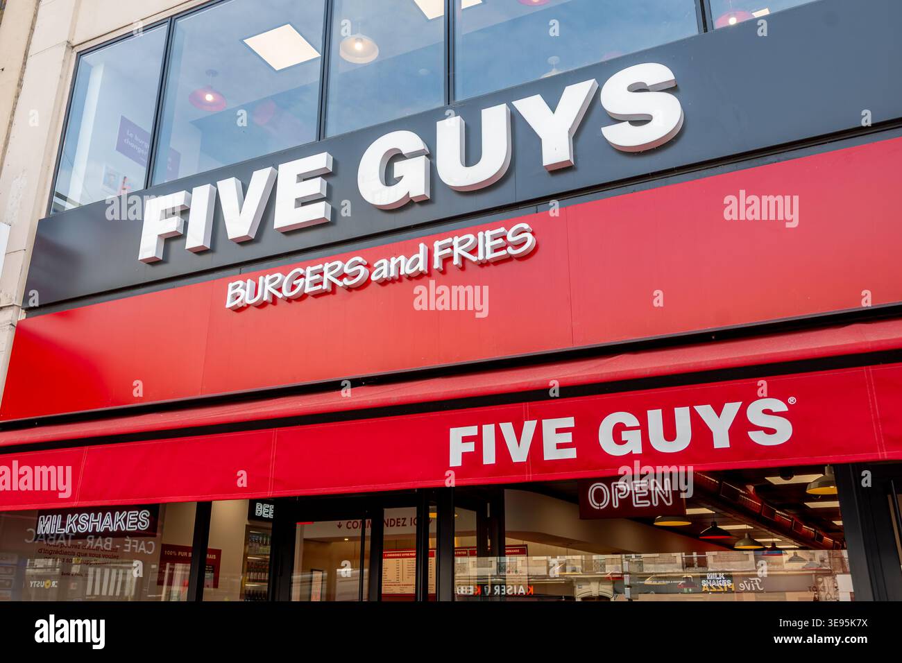 Cartelli e logo all'ingresso di un ristorante Five Guys. Five Guys Enterprises, LLC è una catena di fast-food americana Foto Stock