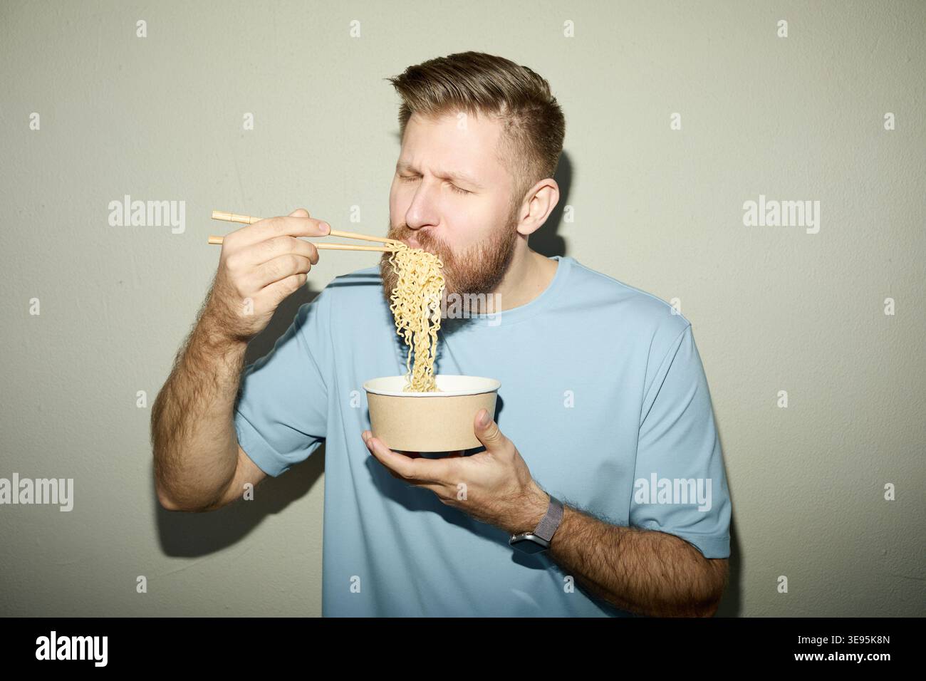 Uomo adulto che mangia spaghetti istantanei per un pasto veloce Foto Stock