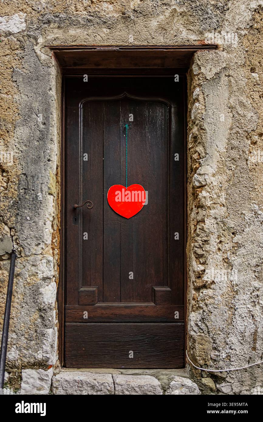 una porta frontale di legno scuro con un cuore rosso al centro Foto Stock