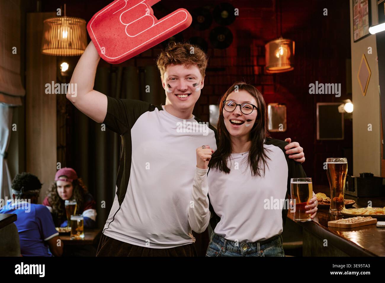 Ritratto degli appassionati di sport adulti che festeggiano al bar durante la serata di gioco Foto Stock