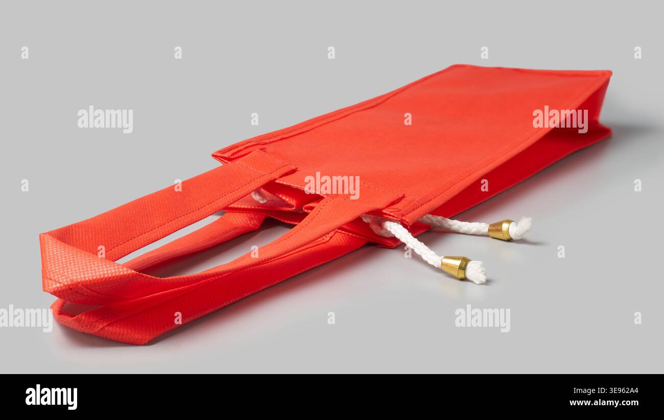 borsa per la spesa vuota in tessuto rosso su sfondo grigio, manici in corda bianca con punte metalliche dorate, modello per mockup con vista laterale, confezione per la vendita al dettaglio Foto Stock