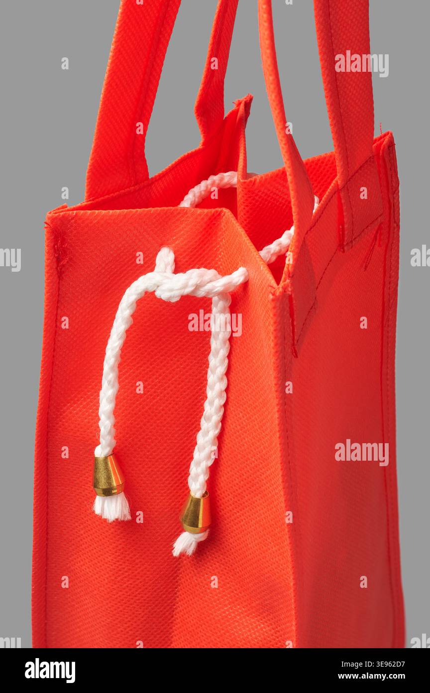 primo piano dell'apertura superiore della borsa della spesa in tessuto rosso con cordoncino intrecciato bianco, aglet o punte metalliche dorate, vista laterale del pacchetto di lusso per la vendita al dettaglio Foto Stock