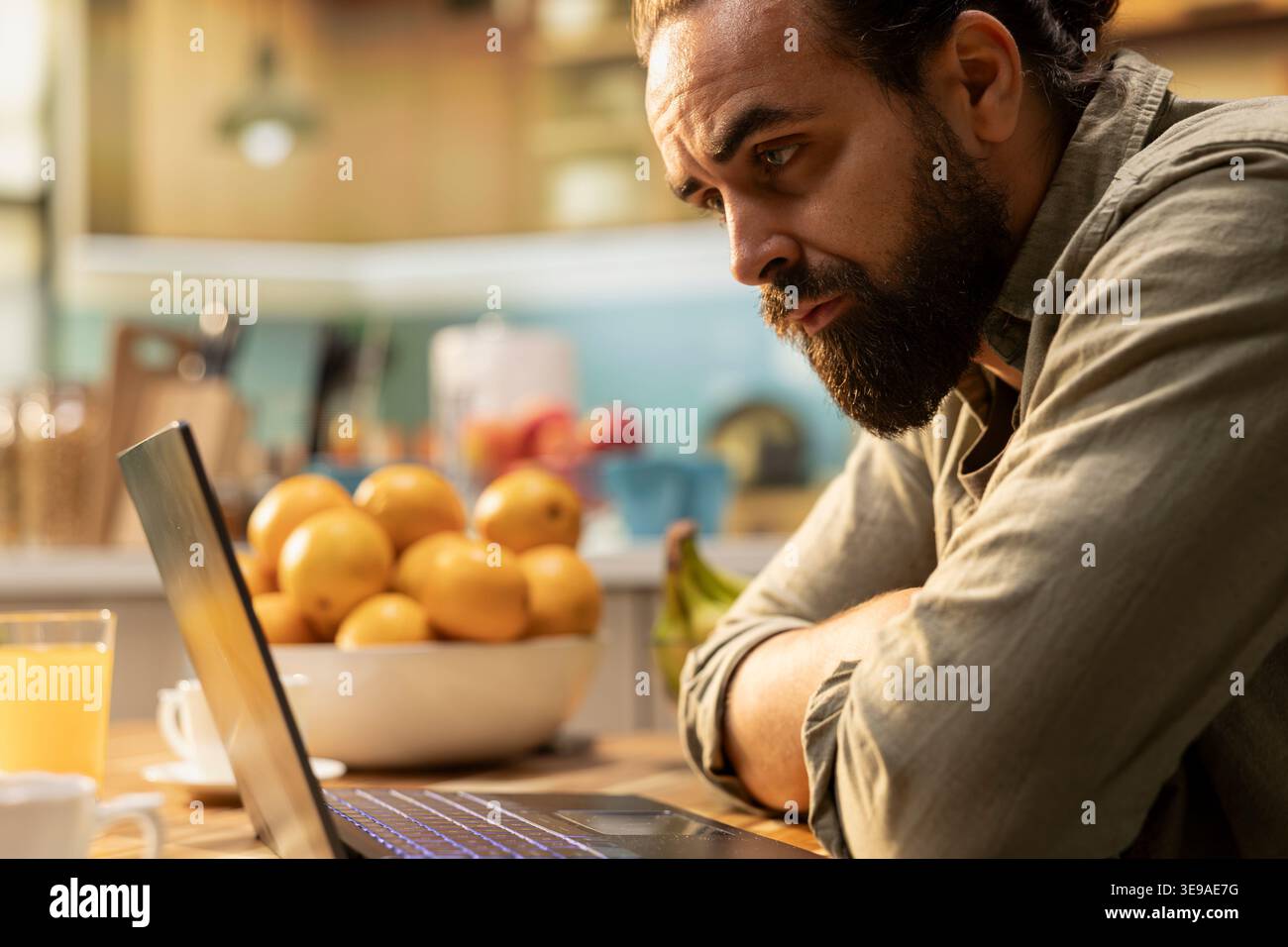 Uomo sgomento, schermo di un notebook, disorientato e incerto, uomo disorganizzato incerto, errore o malinteso al tavolo della cucina. Ambiguo, confuso libero professionista, preoccupato per il telelavoro. Foto Stock