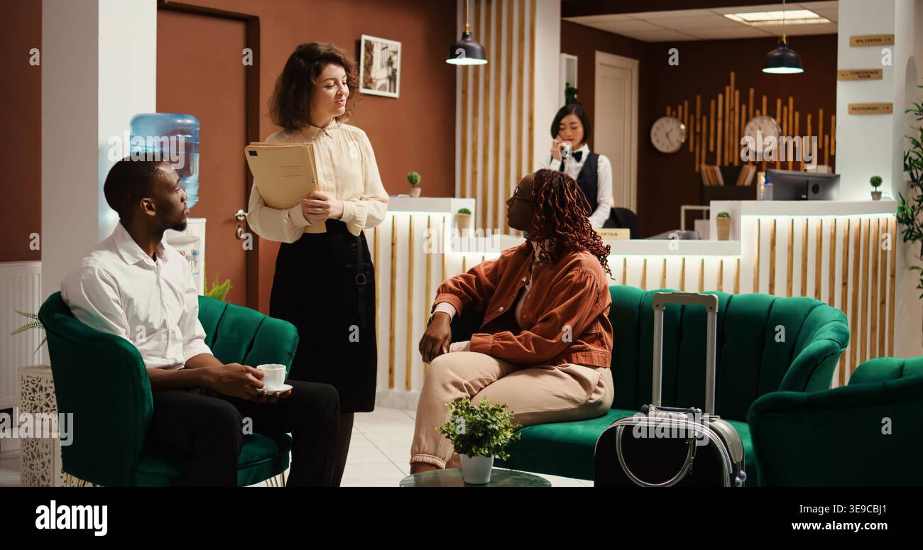 L'amministratore dell'hotel vende ospiti in attesa, offrendo servizi extra e upgrade delle camere. I turisti discutono con il manager delle opzioni di pacchetti vacanza in residence, ingrandiscono le foto Foto Stock