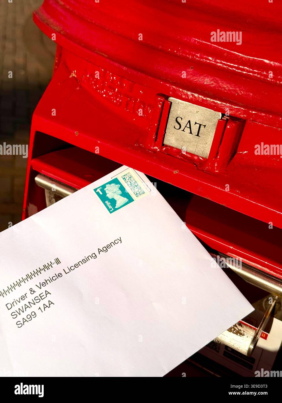 Una lettera con un francobollo di prima classe in una casella postale della Royal mail Foto Stock