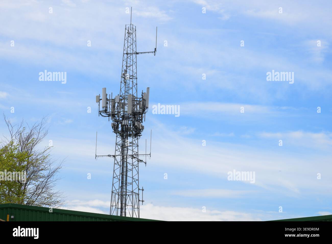 Torre di comunicazione cellulare con più antenne e trasmettitori sotto il cielo blu, che rappresenta la rete mobile, la tecnologia wireless e la connettività Foto Stock