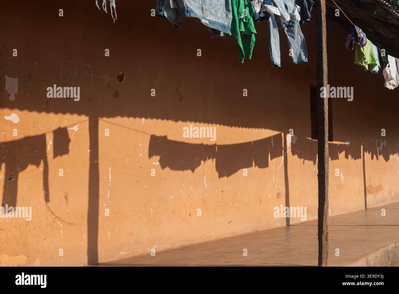 Ombre su una parete di colore terra di biancheria da asciugare sulla linea di stoffa nell'ex capitale Bolama, Guinea Bissau Foto Stock