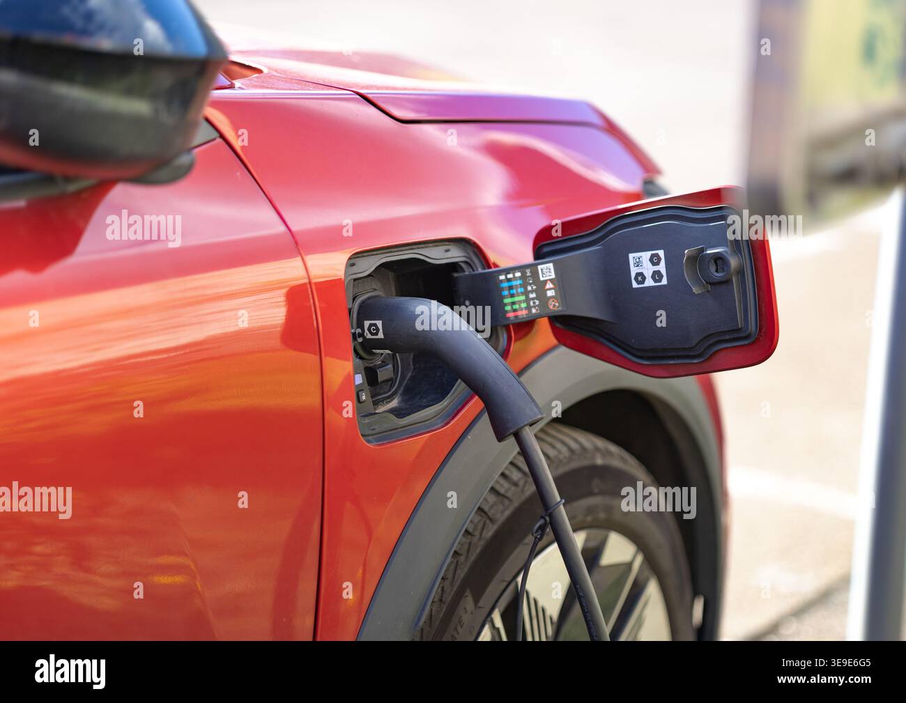 Immagine ravvicinata della maniglia di ricarica di un'auto elettrica collegata alla presa di alimentazione di un veicolo. L'immagine si concentra sul punto di connessione in corrispondenza di un canale fisso Foto Stock