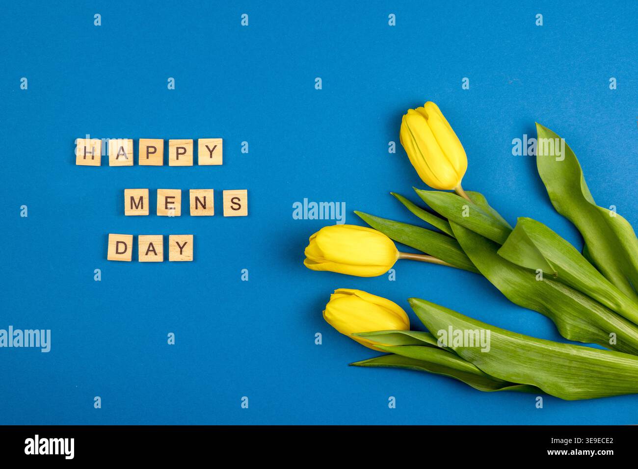 Happy Men's Day background. Tulipani gialli su blu. Tre fiori. Foto Stock