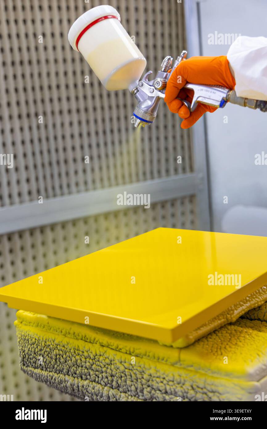 Primo piano del processo di verniciatura industriale dei pannelli gialli con pistola a spruzzo Foto Stock