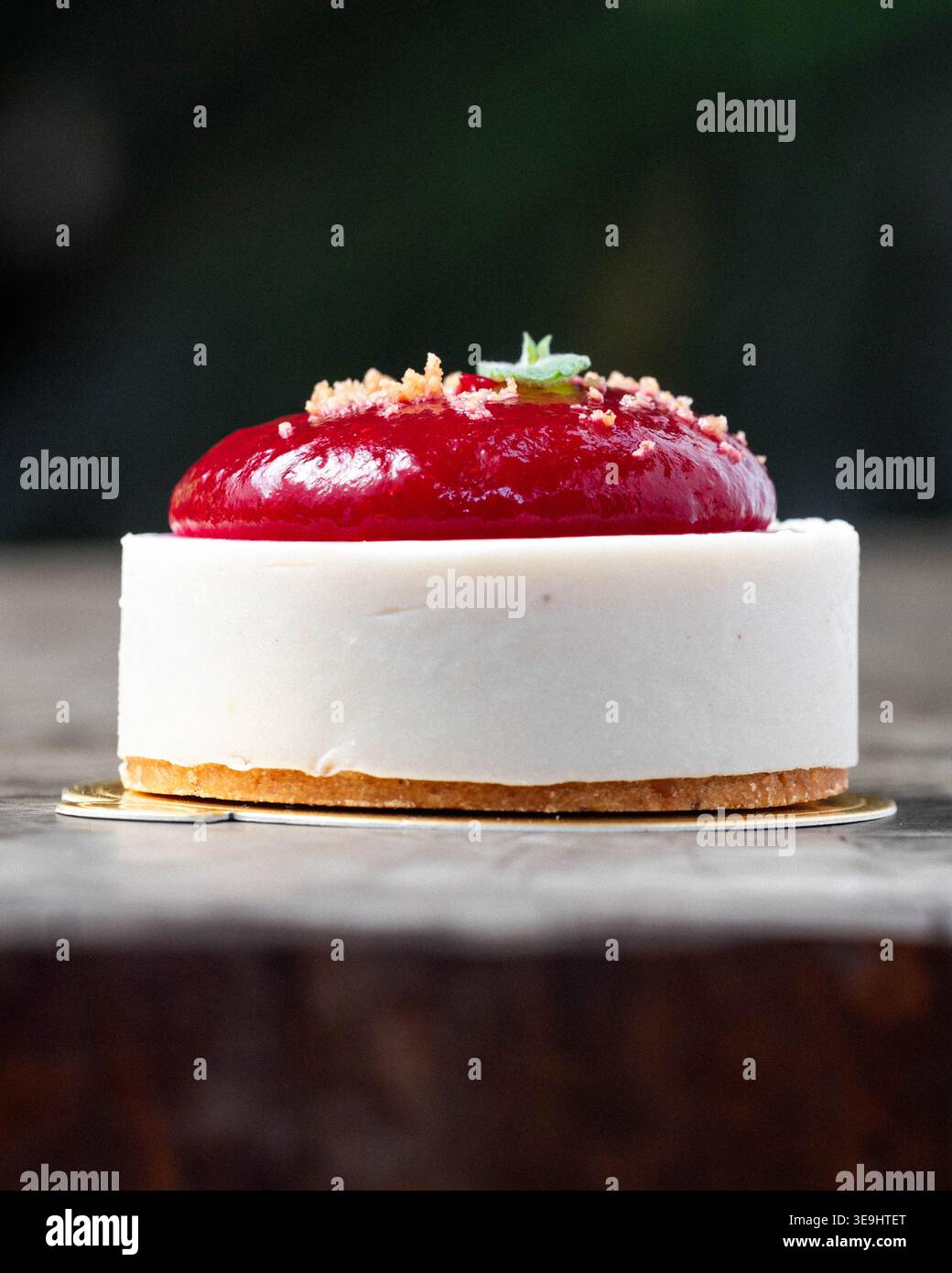 Il dolce delicato poggia su una superficie rustica in legno. La base bianca cremosa contrasta con la superficie rossa brillante. La crosta dorata aggiunge consistenza sotto la torta. Stagno Foto Stock