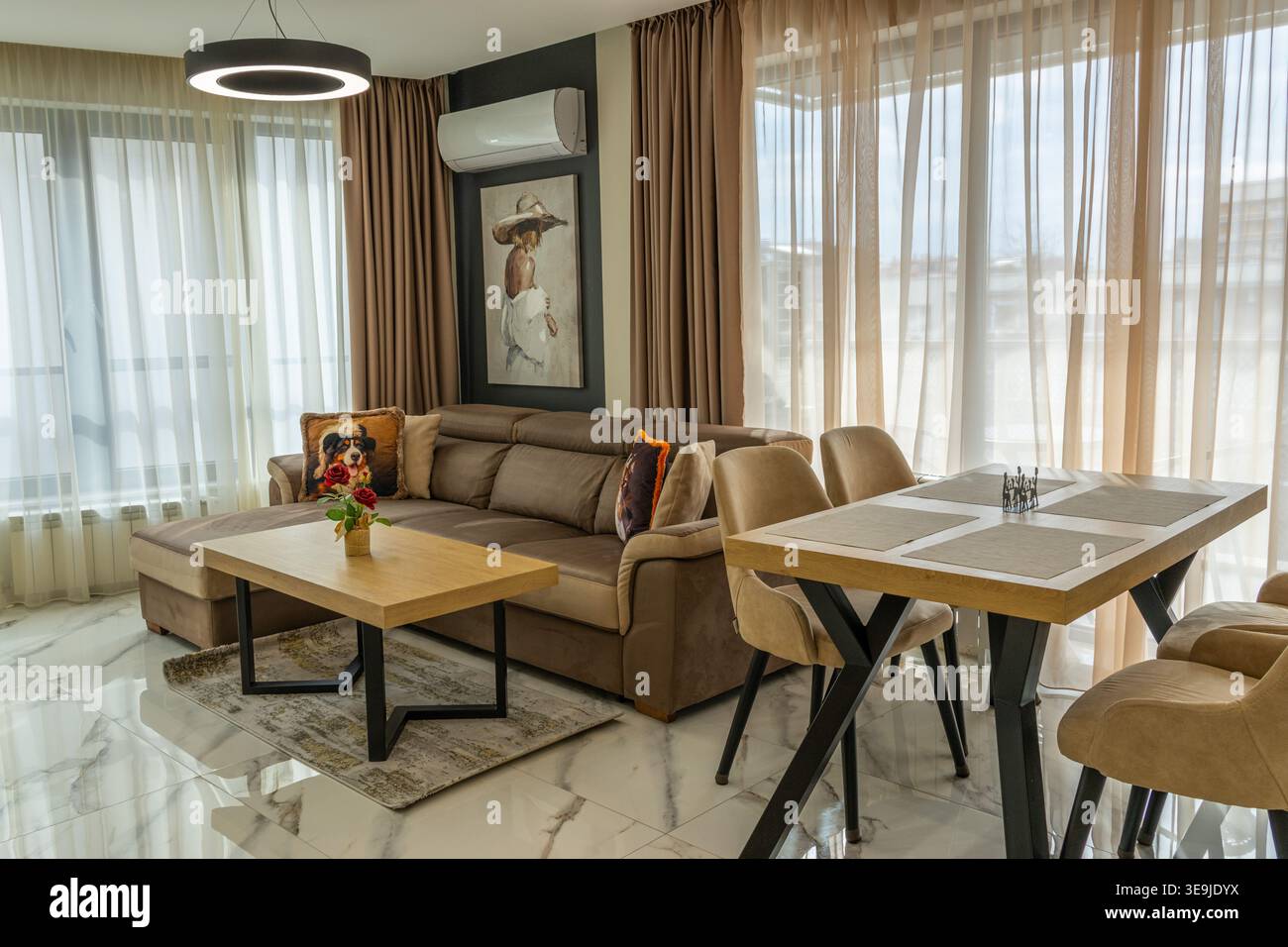 Luminoso appartamento moderno con pavimento in marmo. Dispone di un divano in velluto, tavoli in legno e un elegante lampadario. Esempio perfetto di moderno open-space Foto Stock