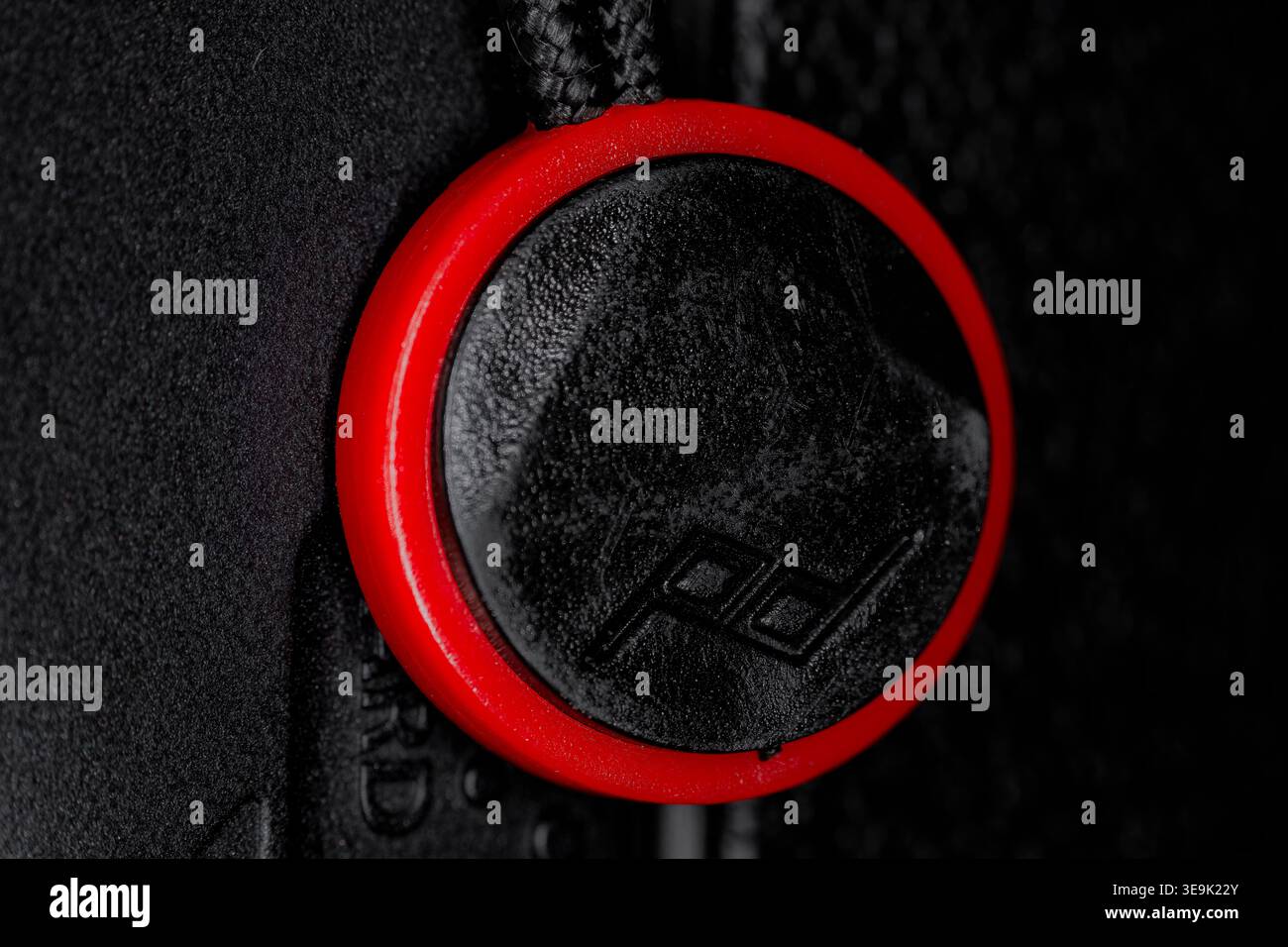 Primo piano dell'ancoraggio con cinturino per fotocamera con anello rosso e connettore nero che mostra dettagli moderni e materiali testurizzati Foto Stock