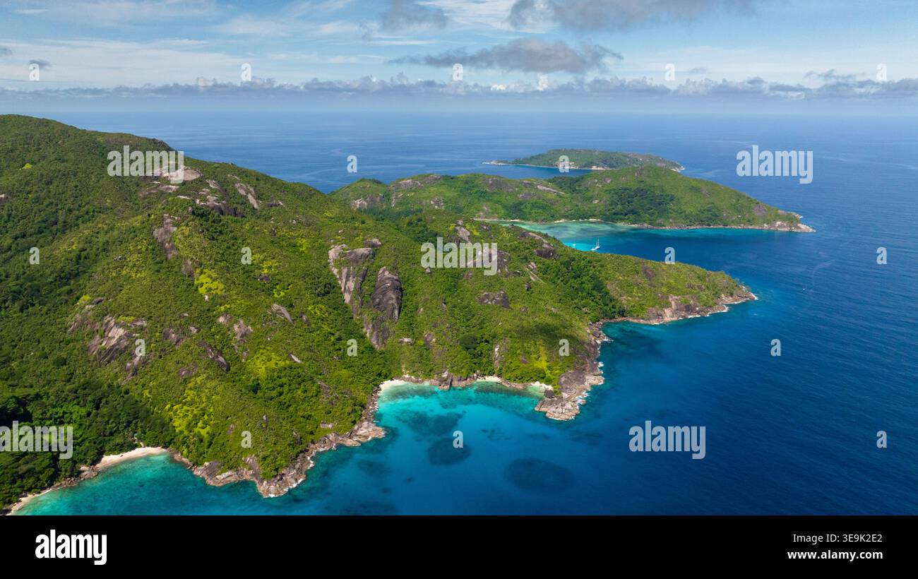 Le ripide montagne verdi scendono bruscamente nelle acque turchesi, delimitate da coste frastagliate. Victoria. Seychelles, Mahe. Foto Stock