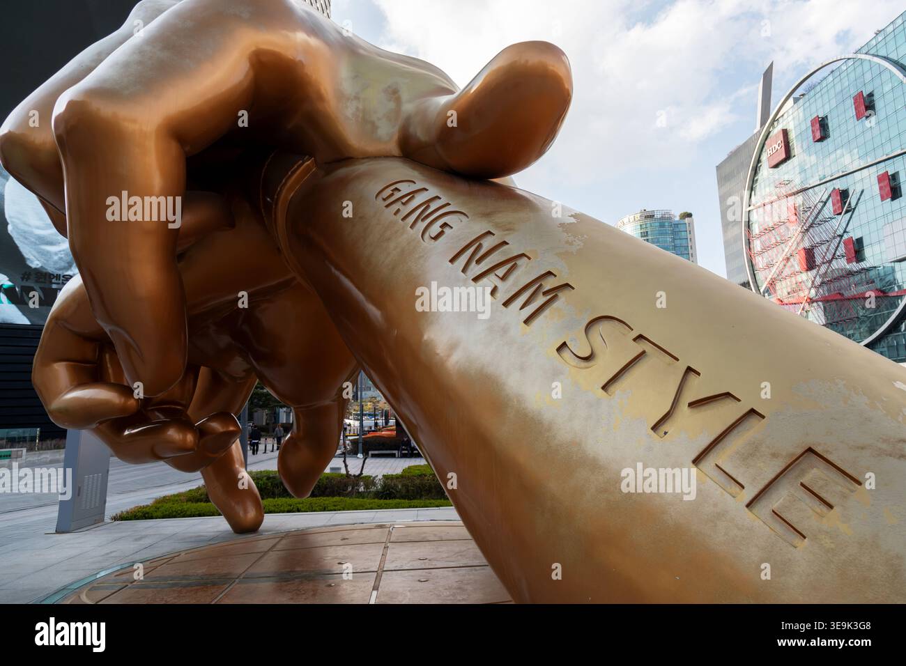Seoul, Corea del Sud - 6 aprile 2026: Grande scultura in bronzo dorato in stile Gangnam, raffigurante due pugni giganti che eseguono l'iconica posa di danza a cavallo di PS Foto Stock