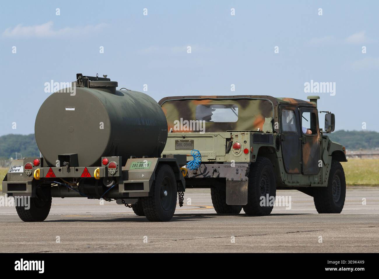 Un Huimmer o Humvee militare utilizza un veicolo con la United States Airforce (USAF) che tira un serbatoio d'acqua alla base aerea di Yokota, Fussa, Tokyo, Giappone. Foto Stock
