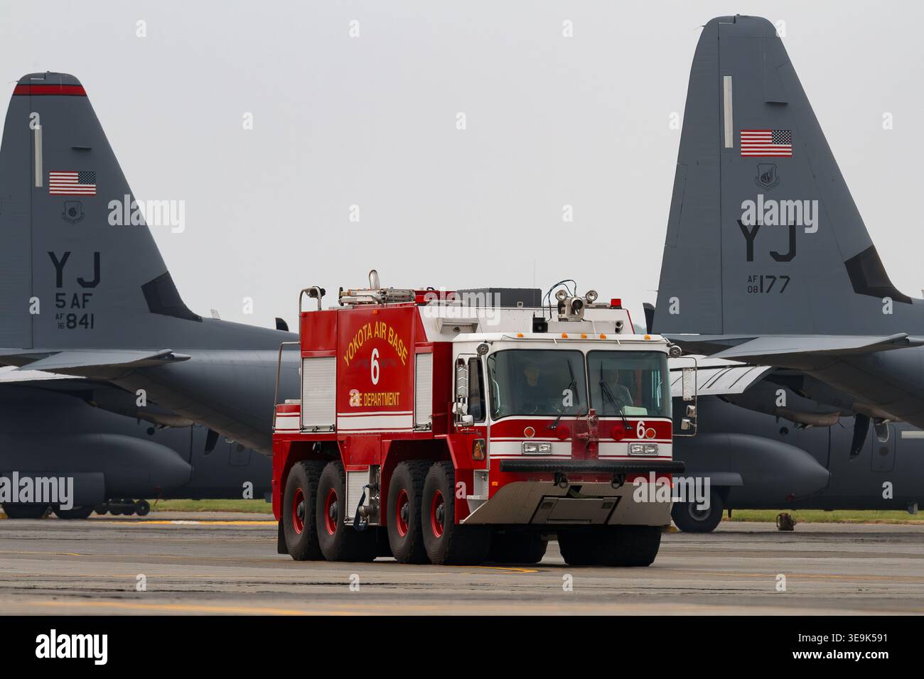 Un camion di soccorso e antincendio P23 con l'USAF a Yokota, base aerea di fronte all'aereo parcheggiato C130J Super Hercules, Tokyo, Giappone. Foto Stock