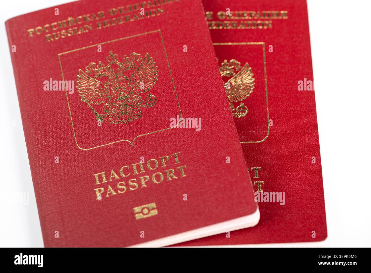 Coppia di passaporti biometrici russi pronti per la verifica dell'identità presso la scrivania amministrativa, coperture testurizzate e microtimbri visibili sotto luce soffusa Foto Stock
