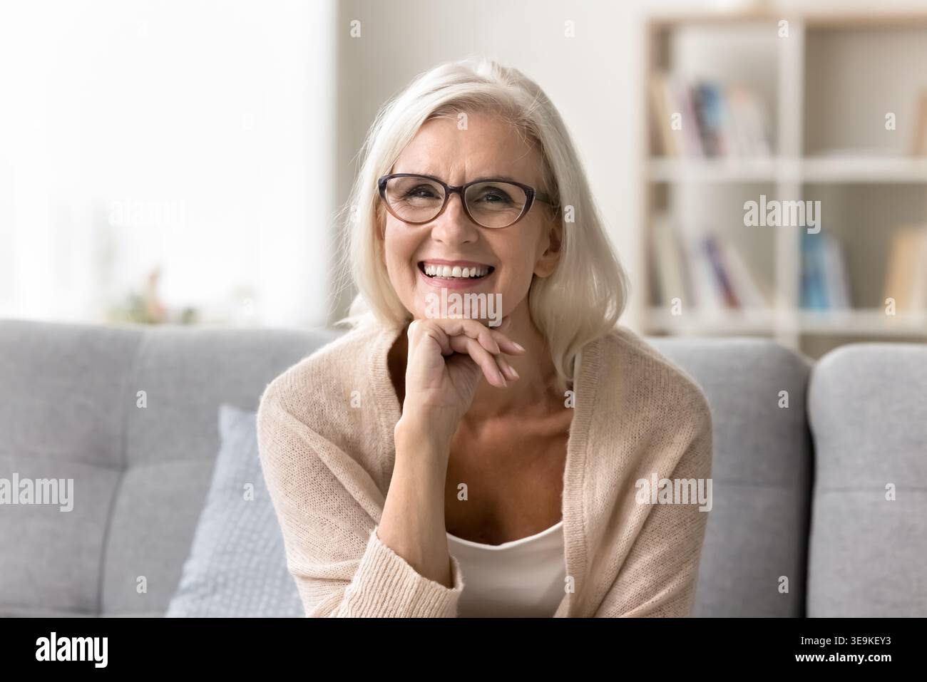 Ritratto di una donna matura che posa per una macchina fotografica seduta sul divano Foto Stock