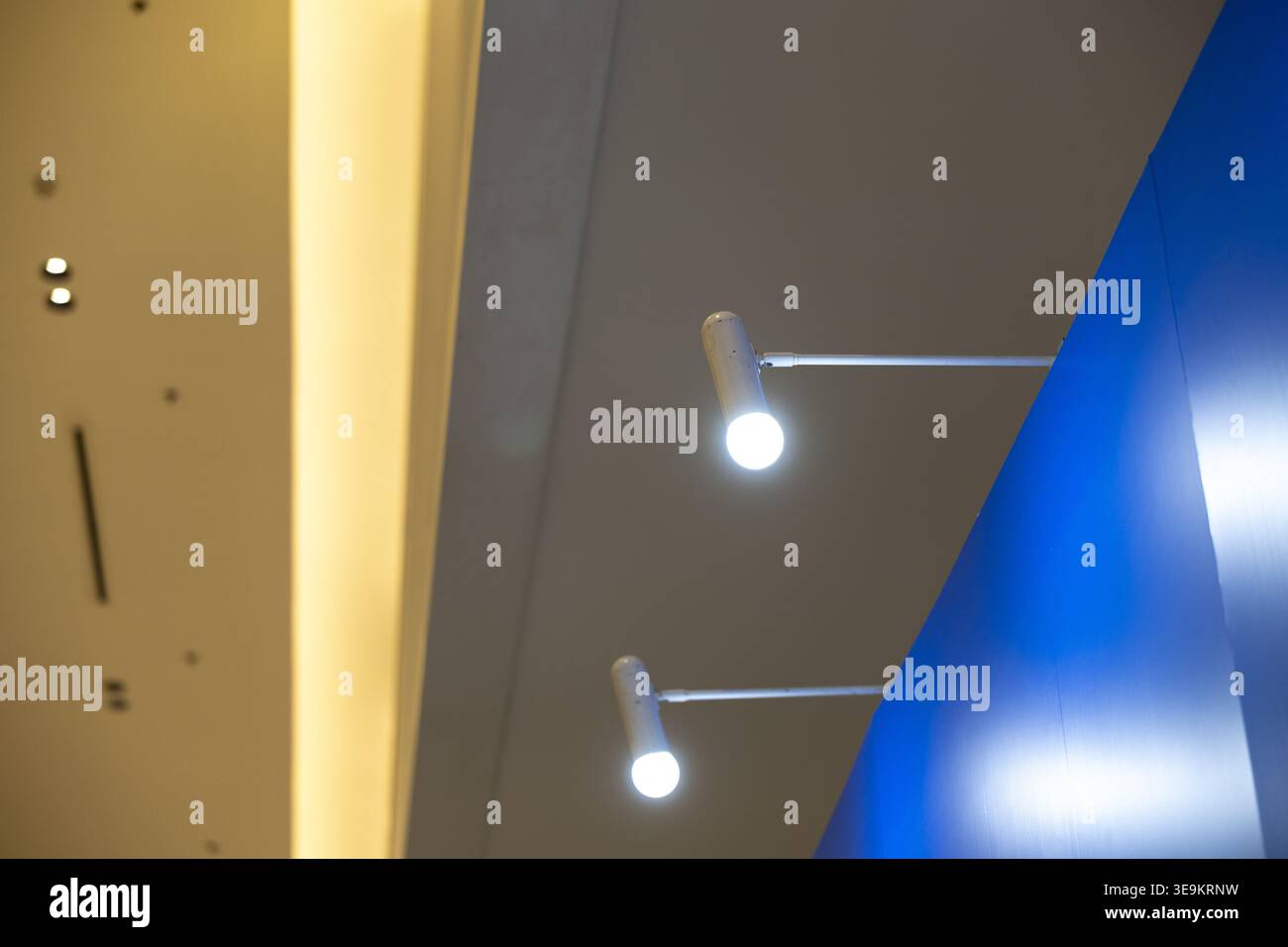 Dettagli interni dall'architettura moderna con pareti blu astratte illuminate da un luminoso faretto sul soffitto che crea un design di illuminazione tranquillo per gli ambienti contemporanei Foto Stock