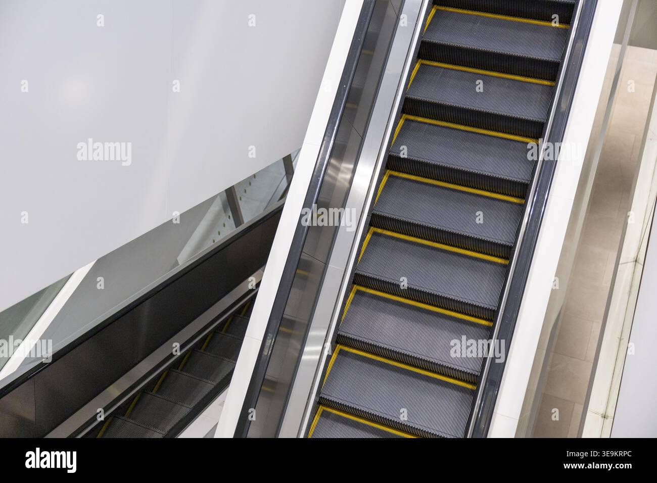 La moderna scala mobile vuota in metallo con linea di sicurezza gialla fornisce un trasporto pubblico interno stabile e calmo che si muove continuamente attraverso il contemporaneo Foto Stock