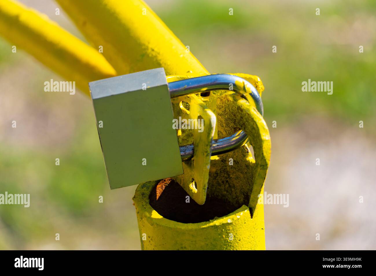 Primo piano di un lucchetto su un cancello barriera in metallo giallo. Concetto di sicurezza, accesso limitato, protezione e proprietà privata Foto Stock
