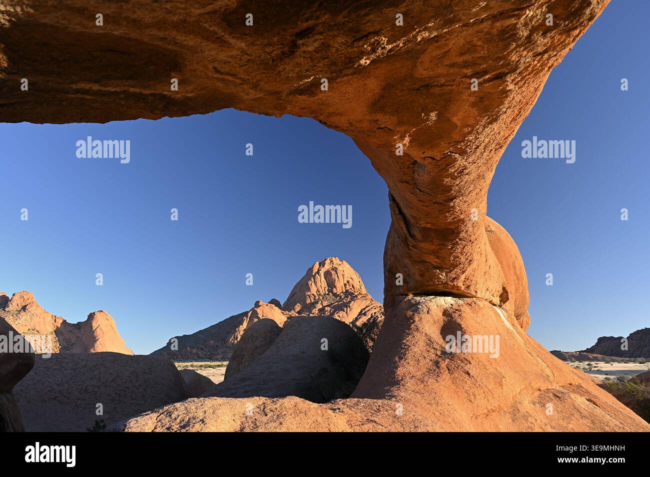 Picco di granito incorniciato da un arco di pietra all'alba a Spitzkoppe, Namibia Foto Stock