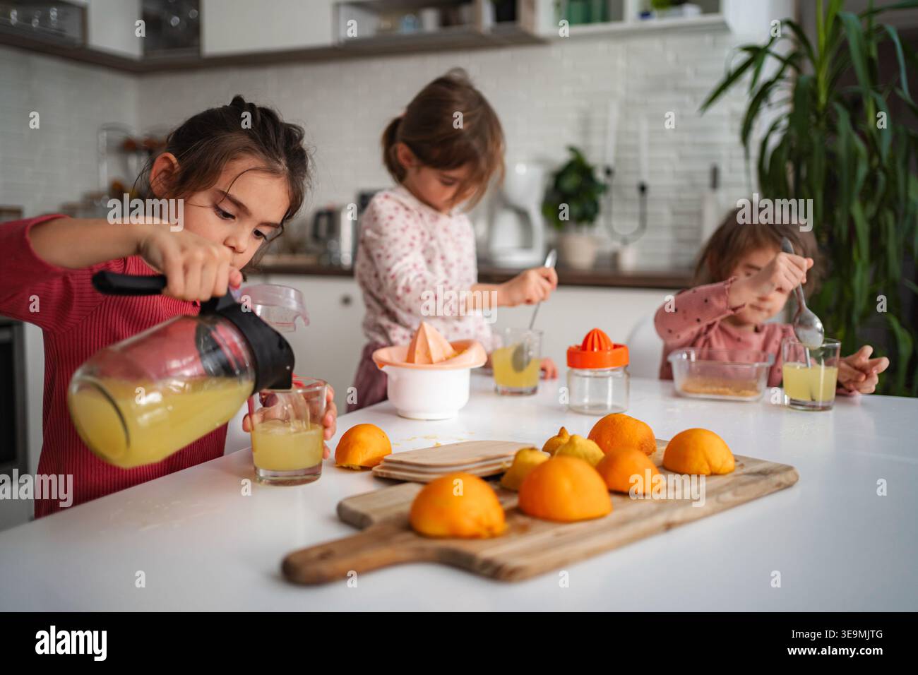 Le sorelle preparano succo d'arancia fresco in cucina Foto Stock