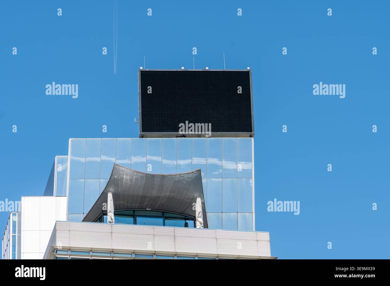 Edificio moderno con grande schermo digitale sul tetto contro il cielo blu. Foto Stock