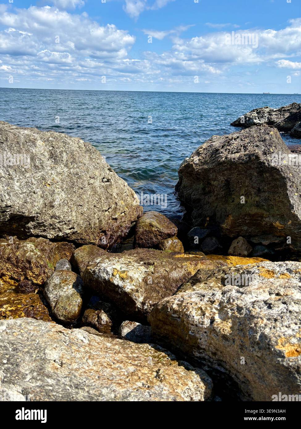 Grandi rocce costiere contro il profondo mare blu e il cielo nuvoloso Foto Stock