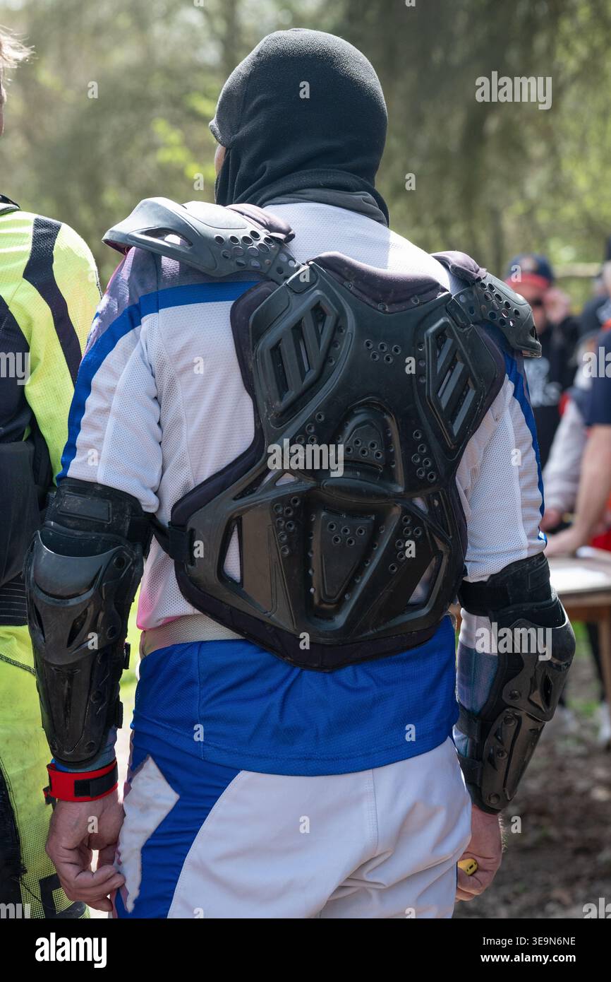 Primo piano di un motociclista da dietro che indossa un'armatura professionale, una protezione per il torace e dei gomiti durante le competizioni enduro. Foto Stock