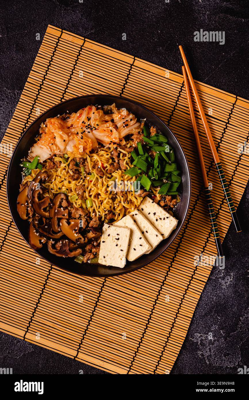 Spaghetti istantanei in stile coreano, Shin Ramyeon con carne macinata, kimchi, formaggio tofu, funghi shiitake. Foto Stock
