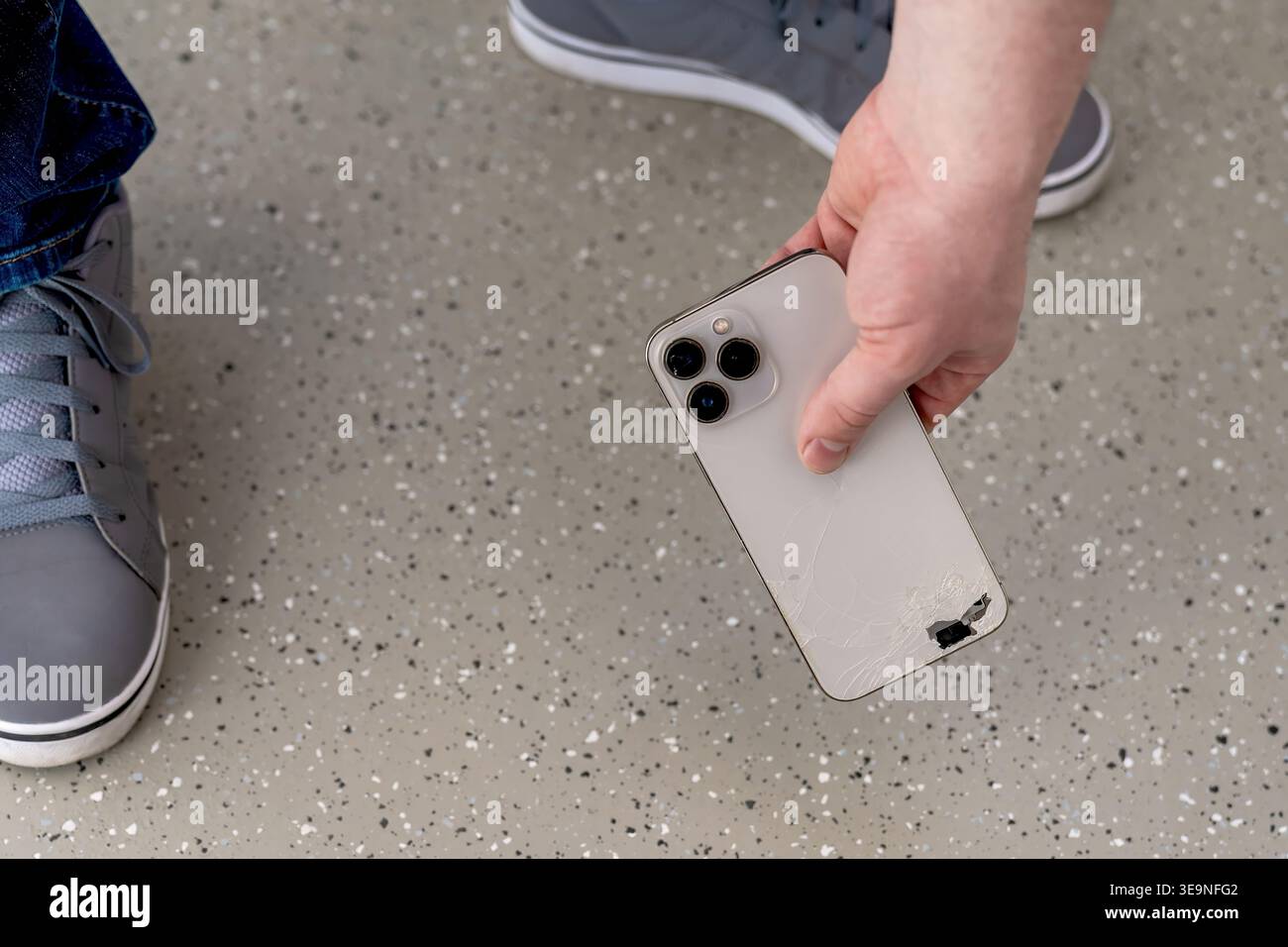 Telefono steso sul pavimento della stazione macchiata vicino alla sneaker, la prospettiva mostra cadute accidentali e portata immediata, momento sincero che trasmette urgenza, pubblico Foto Stock