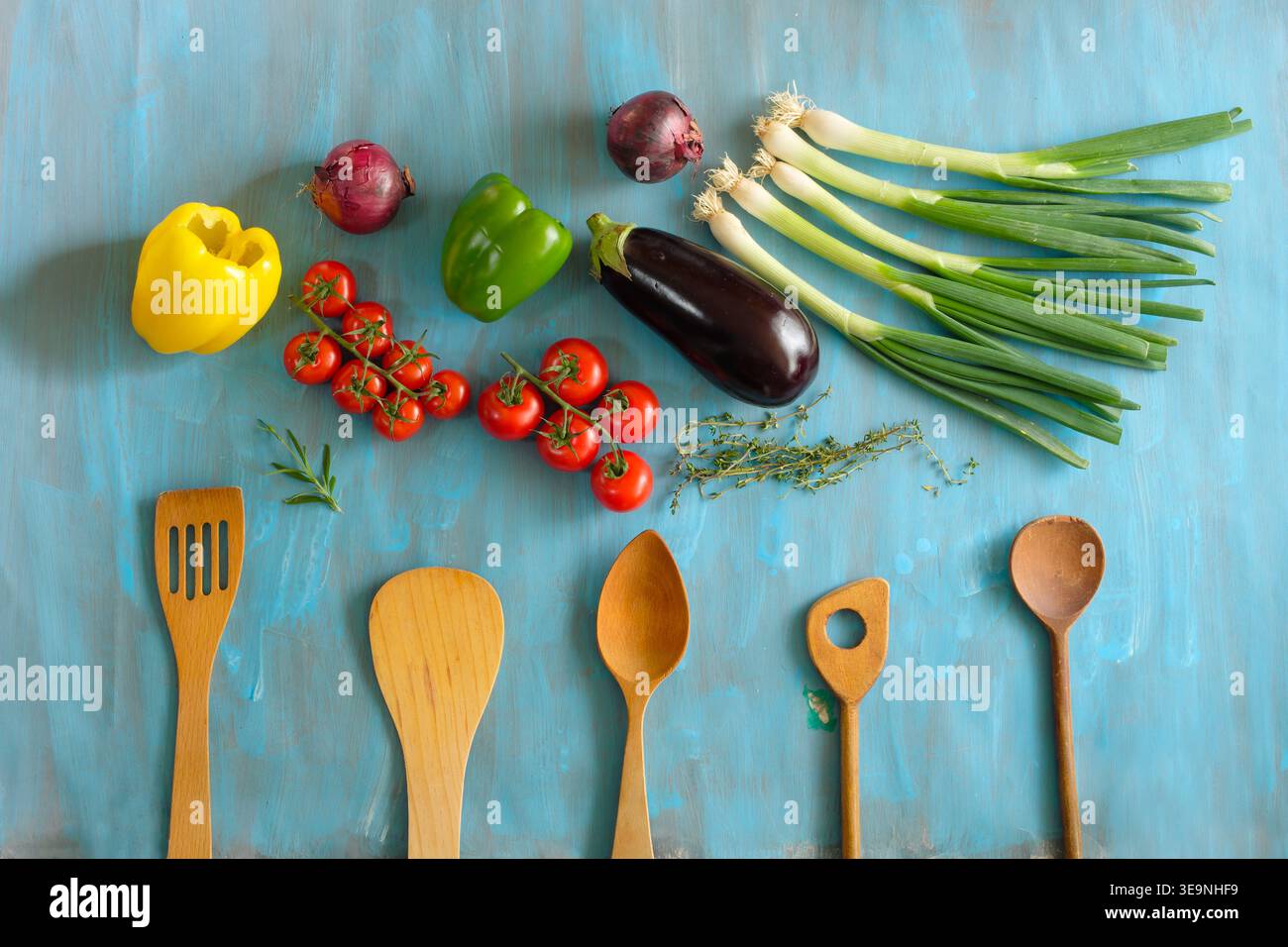 Cucchiai di legno e verdure fresche su sfondo blu Foto Stock
