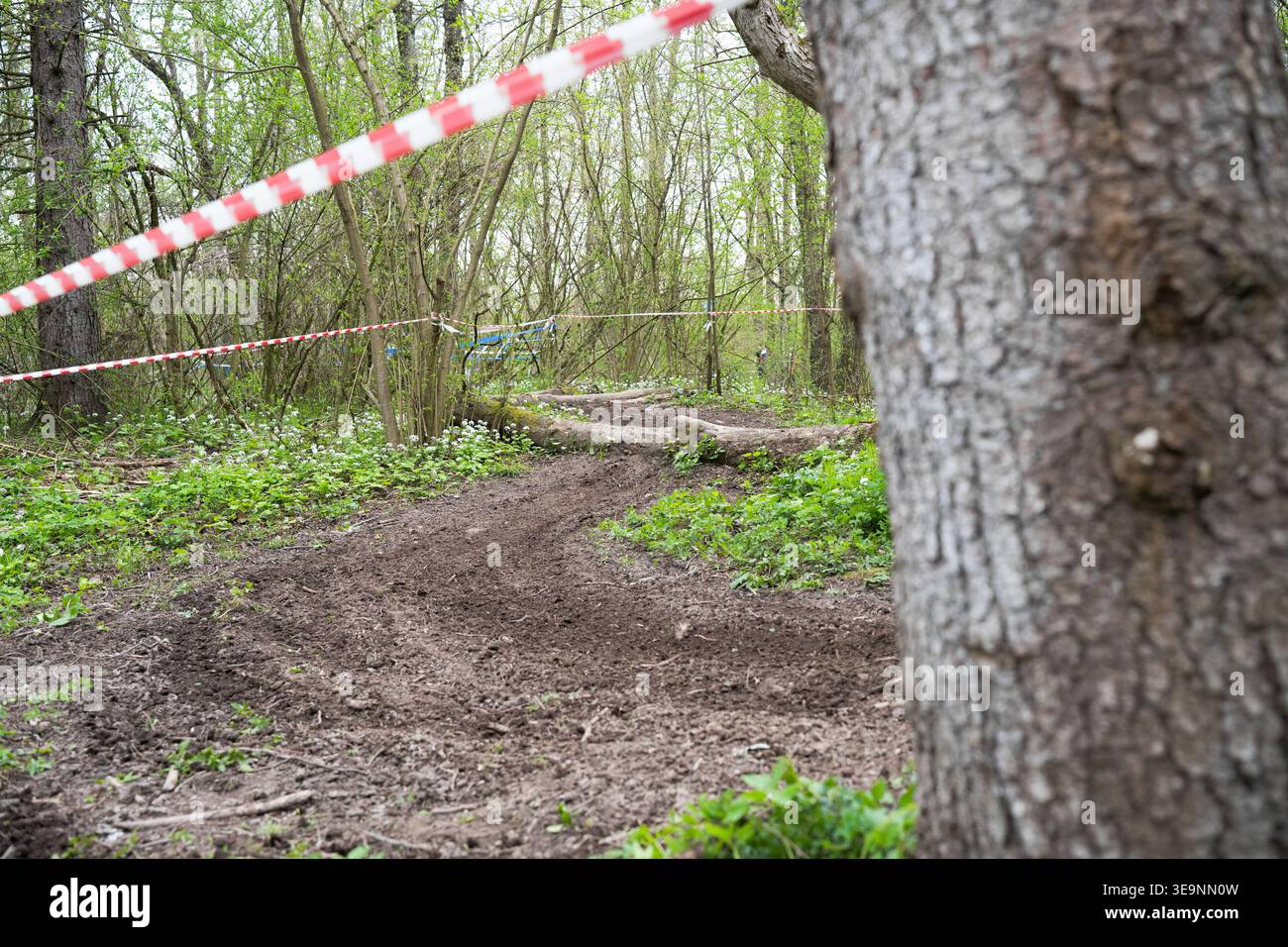 Pista sterrata vuota con ostacoli in legno e nastro isolante nella foresta, preparata per una gara di enduro e motocross. Foto Stock