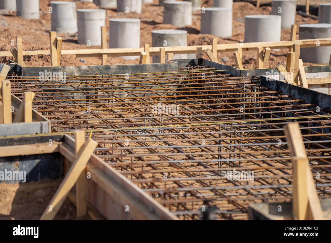 Tappetino di rinforzo per armature all'interno della cassaforma di lastre in calcestruzzo in cantiere di impianti solari con rinforzo in legno e manicotti di fondazione in calcestruzzo visibili Foto Stock