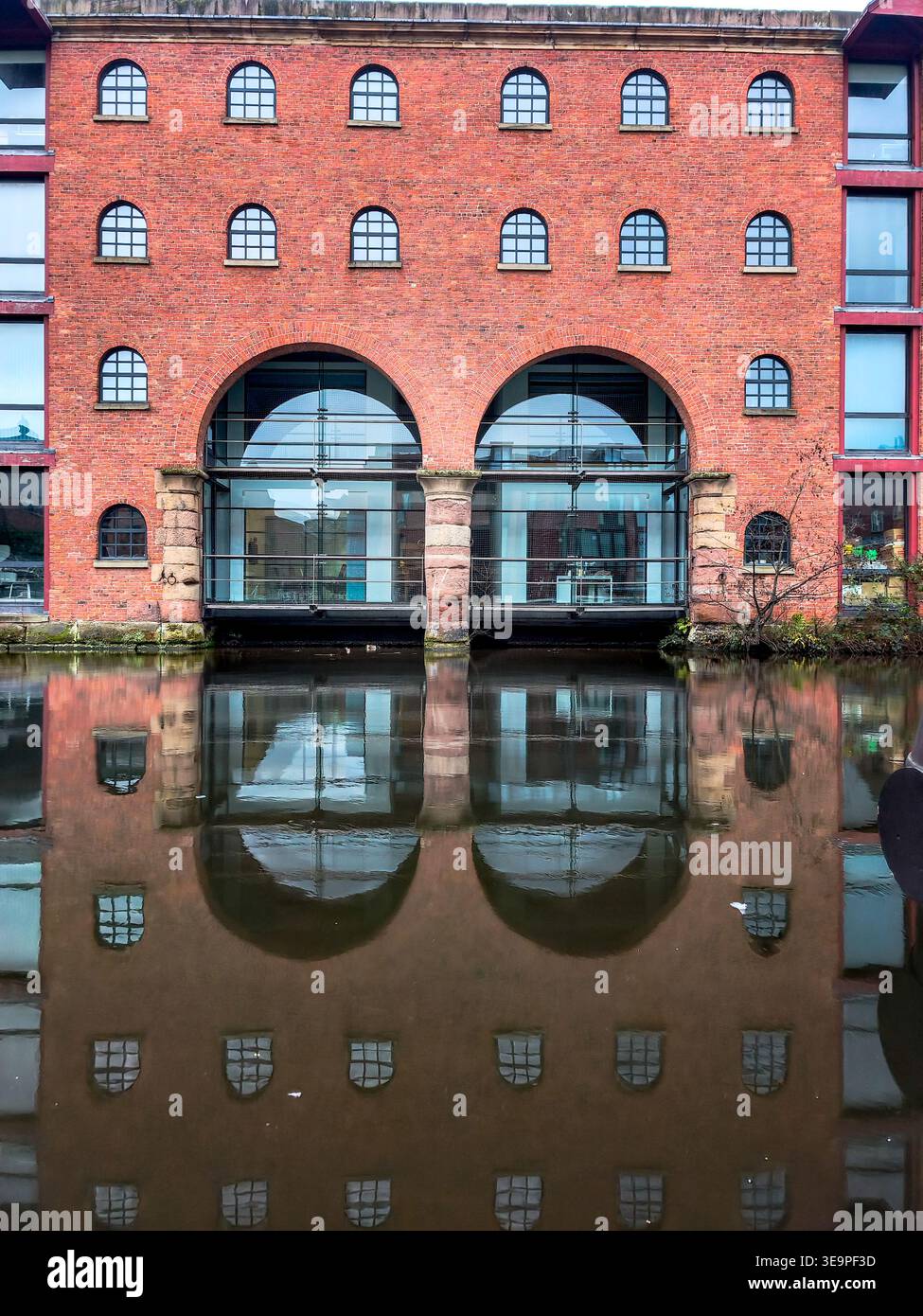 Un edificio in mattoni con finestre ad arco e una grande finestra sul fronte. L'edificio è circondato dall'acqua Foto Stock